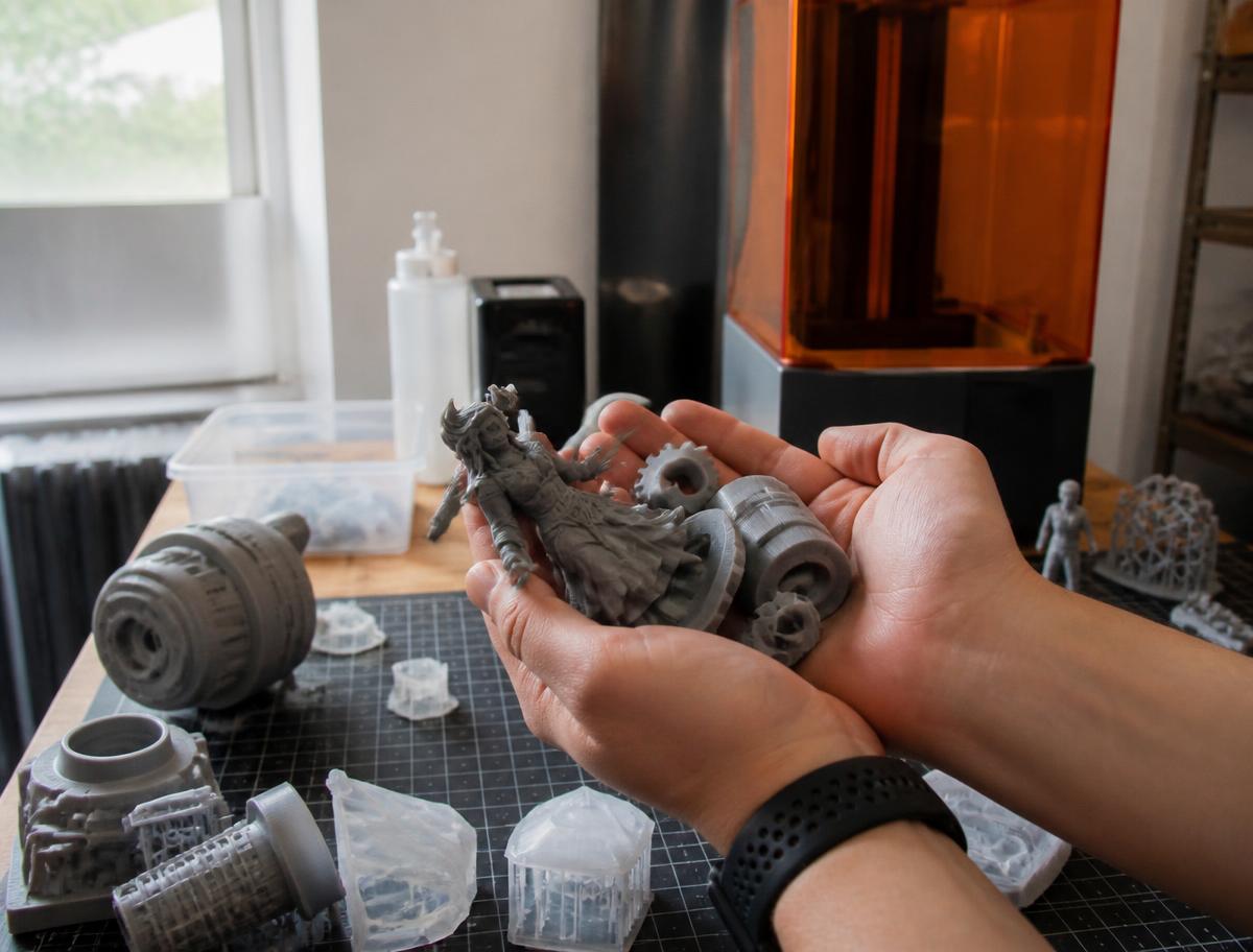 Mãos segurando peças e miniaturas impressas em 3D